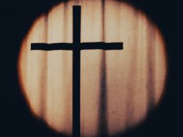 ein-kreuz-ist-durch-ein-rundes-fenster-zu-sehen-j93RfbkK0P4