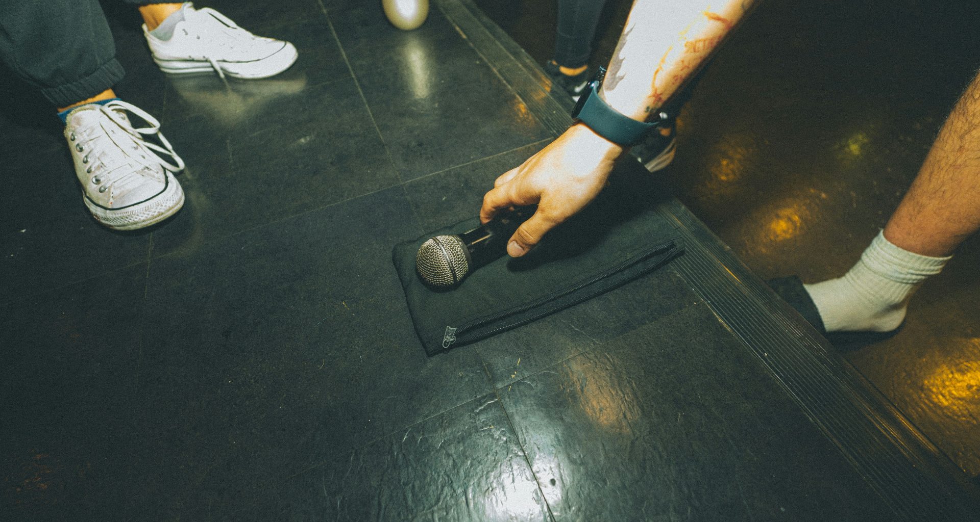 eine-person-die-ein-mikrofon-auf-einem-schwarzen-boden-halt-Ngl4R1V8ByE