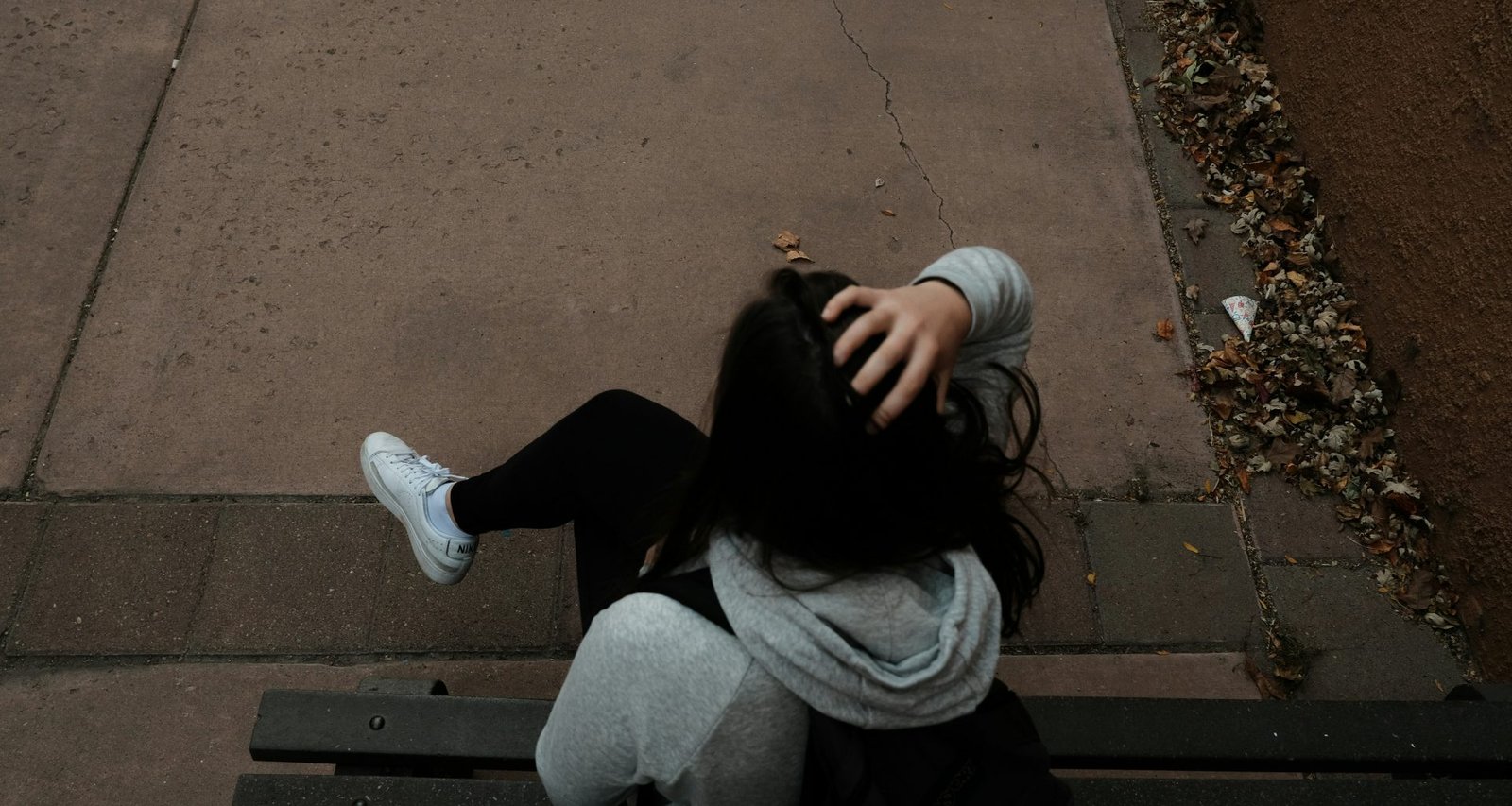 eine-person-die-auf-einer-bank-auf-einem-burgersteig-sitzt-guefe7-LVZY