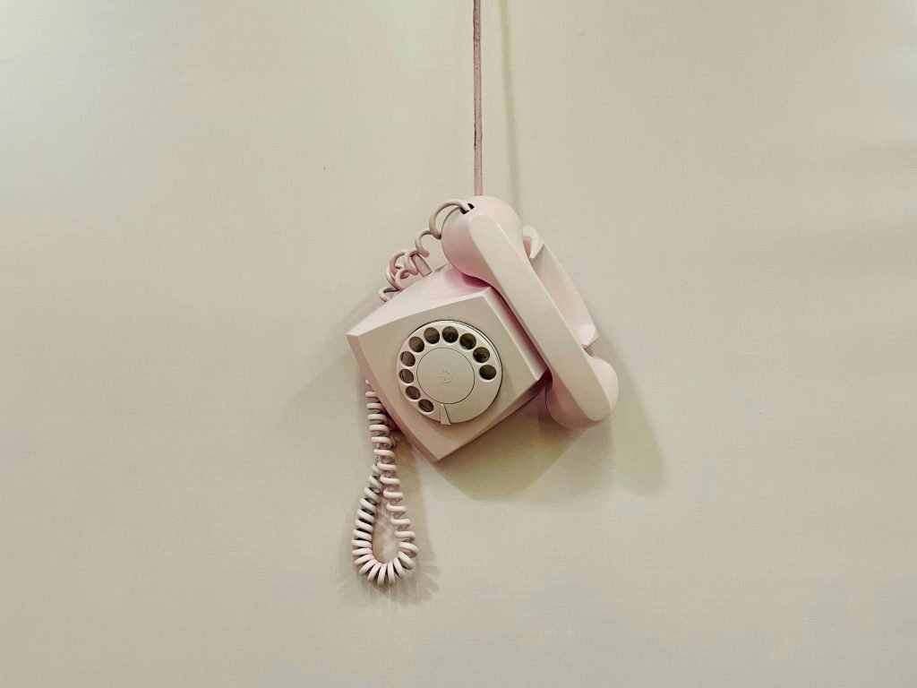ein-rosafarbenes-telefon-das-an-einem-kabel-an-einer-wand-hangt-MwNAvpuqycc