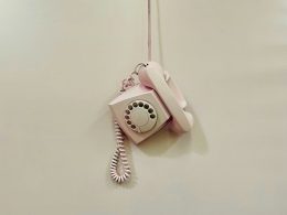 ein-rosafarbenes-telefon-das-an-einem-kabel-an-einer-wand-hangt-MwNAvpuqycc