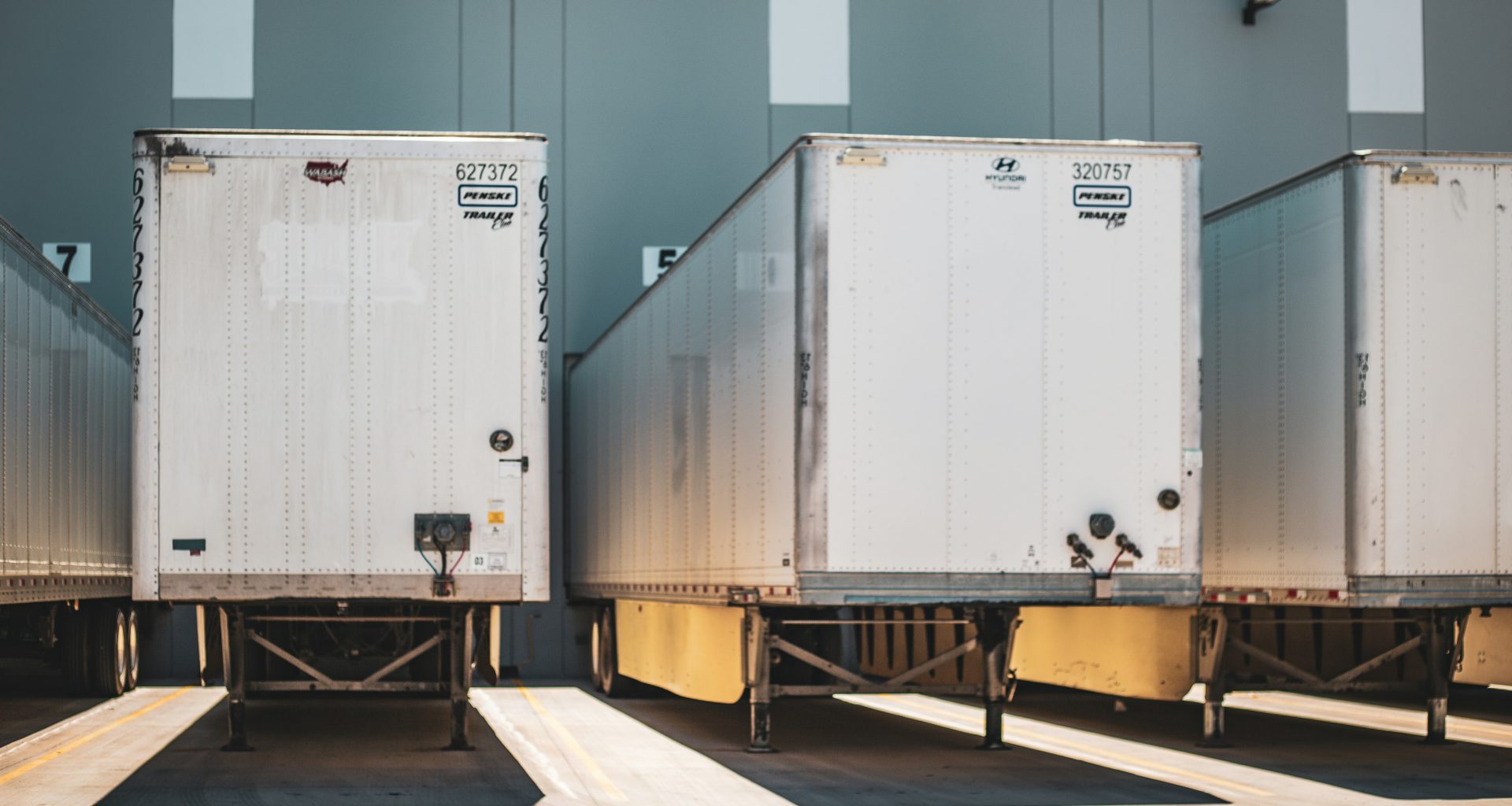 eine-reihe-nebeneinander-geparkter-sattelschlepper-fP4OG67TVes