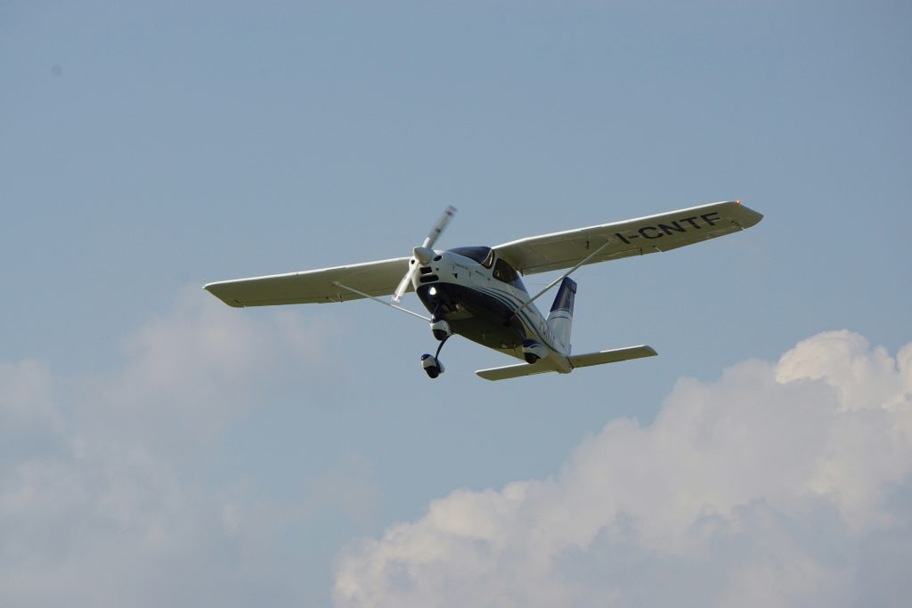 ein-kleines-flugzeug-das-durch-einen-wolkenverhangenen-blauen-himmel-fliegt-5lY0pl27kHM