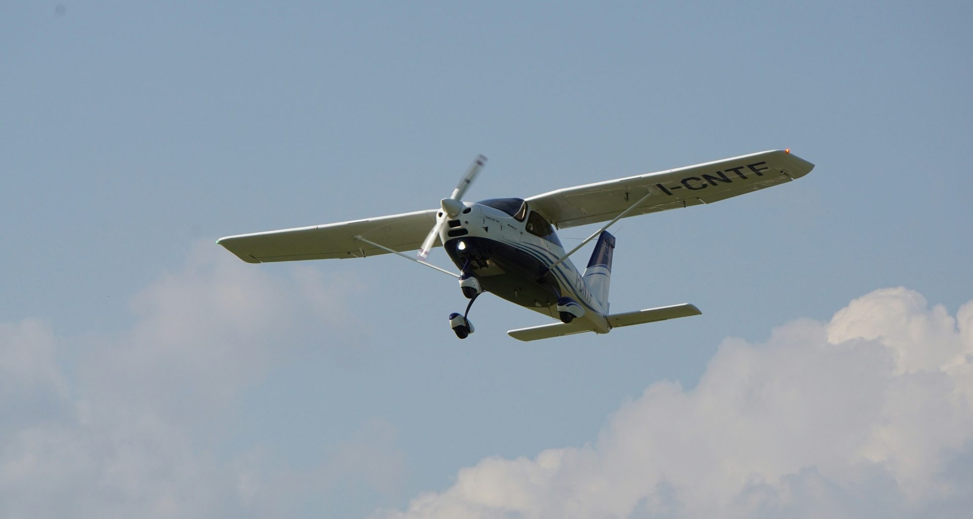 ein-kleines-flugzeug-das-durch-einen-wolkenverhangenen-blauen-himmel-fliegt-5lY0pl27kHM