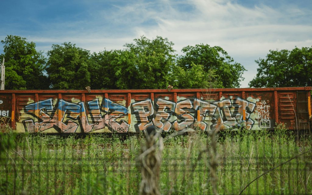 ein-mit-graffiti-bedeckter-zug-der-auf-einem-bahngleis-sitzt-Sn6XaMKPXCk