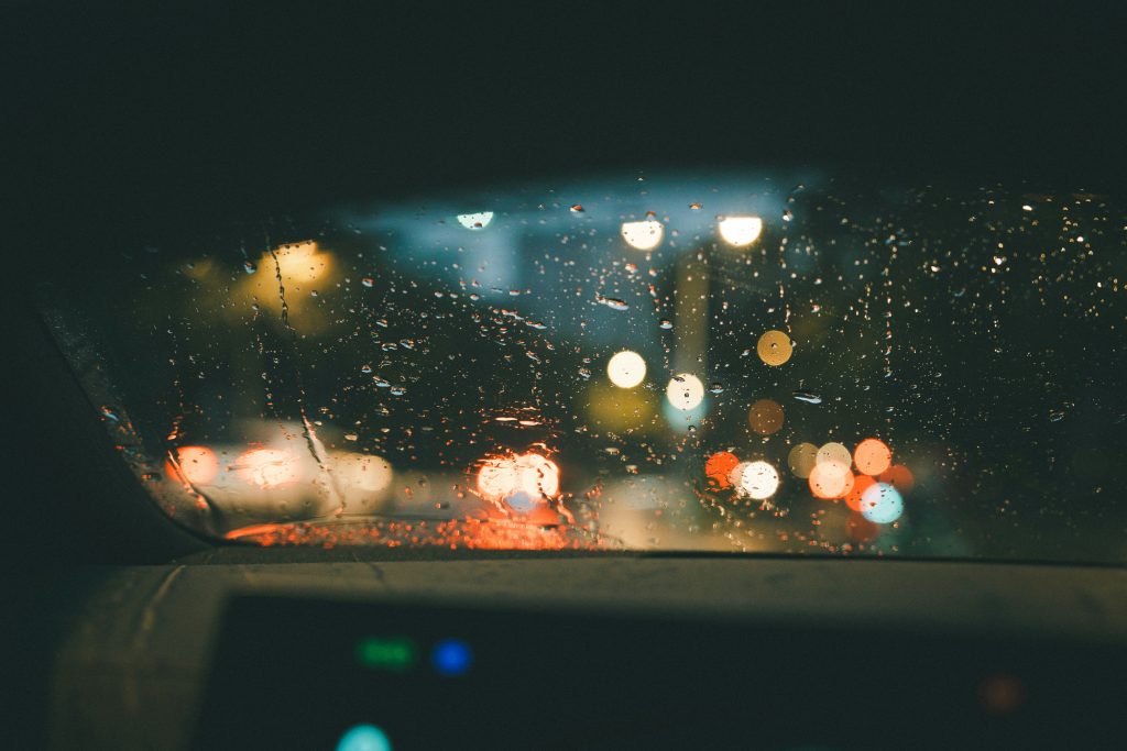 blick-auf-eine-regenbedeckte-windschutzscheibe-aus-dem-inneren-eines-autos-R-9w8yLlZdg