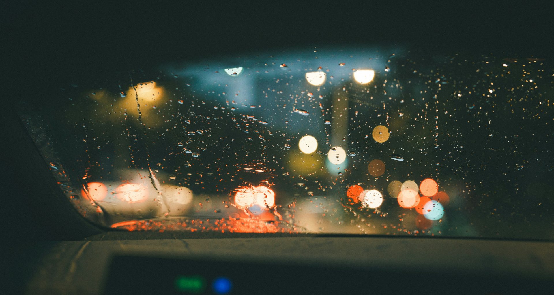 blick-auf-eine-regenbedeckte-windschutzscheibe-aus-dem-inneren-eines-autos-R-9w8yLlZdg