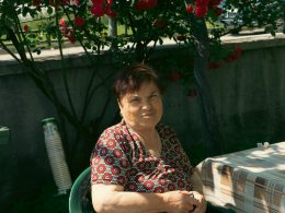 eine-frau-die-an-einem-tisch-mit-einem-bluhenden-baum-im-hintergrund-sitzt-7lYjOJ8VpEo