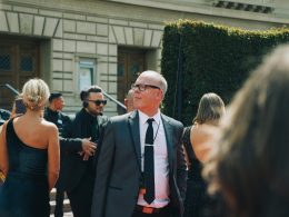 mann-im-schwarzen-anzug-steht-neben-frau-in-schwarzem-armellosem-kleid-86FS7rESSg0