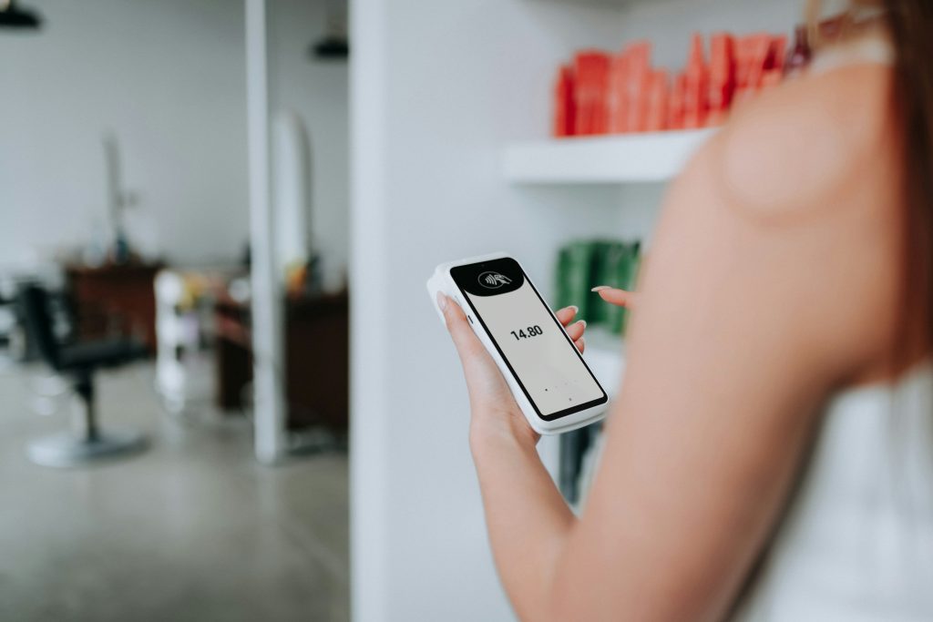 jemand-halt-ein-zahlungsterminal-in-einem-salon-in-der-hand-G723VoGXuBg