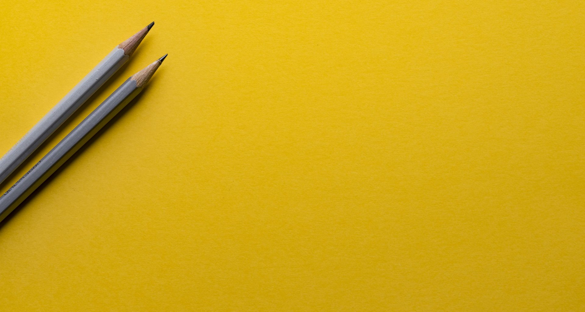 zwei-graue-bleistifte-auf-gelber-oberflache-1_CMoFsPfso