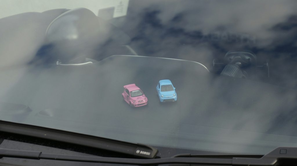zwei-kleine-spielzeugautos-auf-einem-armaturenbrett-5YYIwej2HLo