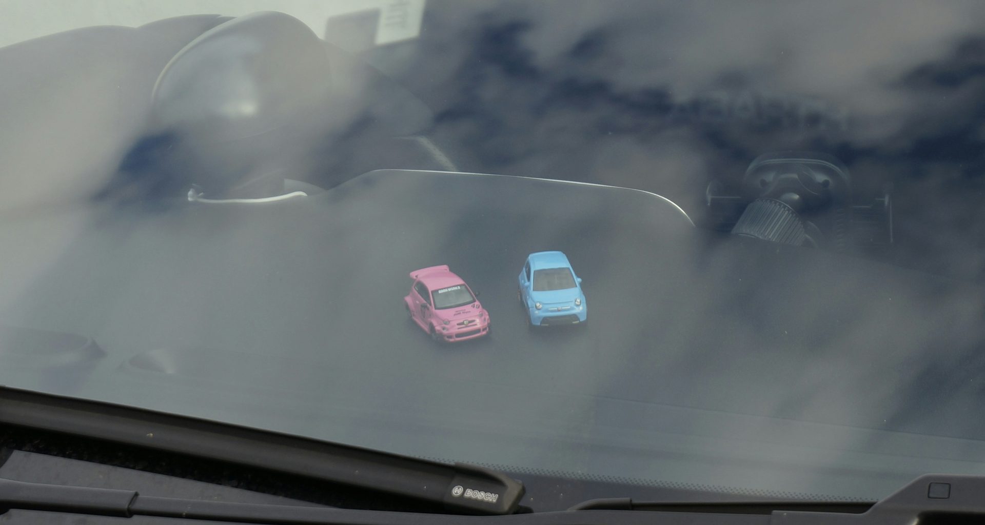 zwei-kleine-spielzeugautos-auf-einem-armaturenbrett-5YYIwej2HLo