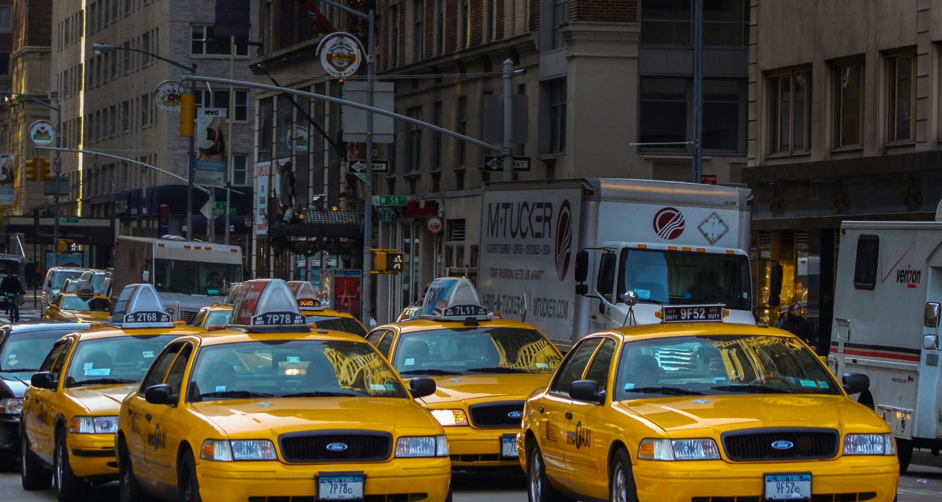 gelbes-taxi-auf-der-strasse-in-der-nahe-des-weissen-betongebaudes-tagsuber-MlZnEM4LUwY