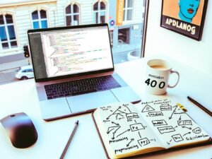 Aufgeräumter moderner Schreibtisch mit aufgeklapptem Laptop, sichtbarem Python-Scikit-learn-Code, Notizbuch mit Machine-Learning-Skizzen, Popkultur-Poster und Kaffeetasse mit 404-Print.