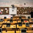 Überfüllte Schulklasse in Deutschland im Jahr 2024 mit alten Holztischen, wenigen Laptops, defektem Whiteboard und handgeschriebenen WLAN-Passwörtern an der Wand – Sinnbild für das digitale Flickwerk im deutschen Bildungssystem.