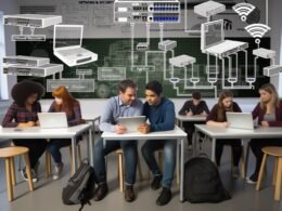 Moderne Schulklasse in Deutschland mit Schülern an Tablets und Laptops, Gruppentischen, interaktiven Whiteboard, offenliegenden Kabeln, WLAN-Routern und digitaler Pinnwand, Lehrer und Administratorin vor großem Technik-Bildschirm