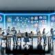 Lichtdurchflutetes, modernes Büro mit mehreren großen Screens, die bunte CRM-Dashboards, Graphen und Analysen zeigen. Im Vordergrund diskutieren Marketer:innen, Data Scientists und Sales-Manager:innen, während im Hintergrund digitale Verbindungen verschiedene Kanäle symbolisieren.