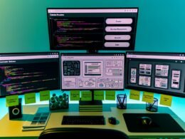 Moderner Entwicklerarbeitsplatz mit mehreren Bildschirmen, auf denen Codezeilen, Datenbankstrukturen und ein Backend-Dashboard mit kreativen Features wie Videoverwaltung und Mehrsprachigkeit angezeigt werden.