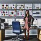 Moderner Büroraum mit Analytics-Dashboards, Marketer ignoriert Papierberichte und betrachtet ein Datenmodell an der Wand, umgeben von Notizen wie Touchpoints, Attribution und Data Warehouse.