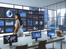 Moderne Kommandozentrale mit großen hochauflösenden Monitoren, die umfangreiche Daten-Dashboards zeigen. Eine fokussierte Person navigiert durch die verschiedenen Visualisierungen, im Hintergrund Glaswände und urbanes Bürodesign.
