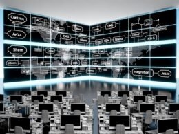 High-Tech-Arbeitsplatz mit großen Bildschirmen, die CMS-Diagramme, API-Codes und JSON-Flüsse präsentieren. Digitale Netzwerke visualisieren eine cloudbasierte, dezentrale Architektur mit klar gekennzeichneten Elementen.