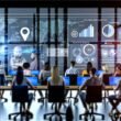Dynamische Büro-Szene mit diversen Menschen vor großen Monitoren voller Datenvisualisierungen und KPI-Dashboards, im Hintergrund dezente Hologramme und KI-Symbole.