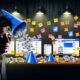 Gestresster Online-Marketer vor chaotischem Schreibtisch mit vielen offenen Tabs, Notizzetteln, Marketing-Tool-Icons und schlechten Conversion-Zahlen