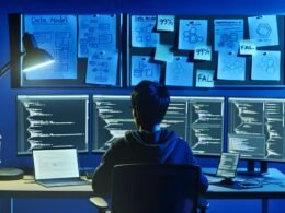 Entwickler am Schreibtisch bei Nacht, vor mehreren Monitoren mit Code, Diagrammen und Strapi-Admin-Oberfläche, moderne Technik und Whiteboard mit Notizen und Datenmodellen