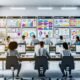 Modernes Büro mit großen Schreibtischen, mehreren Bildschirmen mit Content Creation Plattform und Team bei gemeinsamer Arbeit, digitale Whiteboards im Hintergrund.