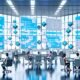 Futuristischer Workspace mit großen Monitoren, diversen Mitarbeitenden und holografischen Content-Blöcken in blau-weißem Licht