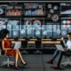 Marketers arbeiten entspannt in einem modernen Büro mit digitalen Dashboards, automatisierten Workflows und Echtzeit-Alerts, umgeben von smarten Geräten ohne gedruckte Berichte.