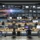 Kreativteam in einem modernen Loft-Büro arbeitet an Laptops und großen Monitoren, umgeben von digitalen Tools für Content-Produktion