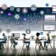 Minimalistische Illustration eines digitalen Arbeitsplatzes mit mehreren Screens, Fachkräften aus Marketing, IT und Data Science, sowie einer Vernetzung von Endgeräten und Social Media Icons.