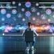 Social Media Manager am futuristischen Arbeitsplatz mit mehreren Monitoren, die Datenströme, Statistiken, Profilbilder und KI-Symbole zeigen