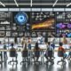 Dynamische Szene in einem modernen Großraumbüro: Junge Marketing-Expert:innen vor mehreren Screens mit Analytics-Dashboards, Datencharts und leuchtenden Vernetzungen zwischen digitalen Geräten.