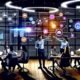 Dynamisches Marketing-Team im modernen Büro diskutiert Daten auf großen Bildschirmen mit Echtzeit-Dashboards, umgeben von Laptops, Tablets und verbundenen Datenquellen.