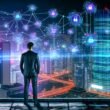 Futuristische Stadt bei Nacht mit leuchtenden Datenströmen, Hochhäusern und einer Person im Business-Outfit vor einem digitalen Bildschirm.