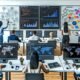 Marketing- und Datenanalyse-Teams arbeiten gemeinsam an Bildschirmen mit Dashboards, Diagrammen, Codezeilen und Datenanalyse-Tools in einem modernen Büro.