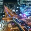 Futuristische Großstadt bei Nacht, mit leuchtenden Datenströmen, autonomen Bussen, Drohnen und digital eingeblendeten Diagrammen vor gläsernen Hochhäusern. Menschen nutzen Smartphones, während Sensoren und Kameras integriert sind.