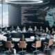 Politiker:innen und Jurist:innen diskutieren an einem runden Tisch in einem modernen Regierungsbüro mit Bildschirmen, die Algorithmusanalysen und Gesetzestexte darstellen.