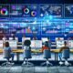 Modernes Büro mit mehreren Monitoren, Echtzeit-Dashboards, Social-Media-Anzeigen und zentraler Serververnetzung, in dem junge Marketer an digitalen Projekten arbeiten.