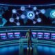 Podcaster in moderner Streetwear steuert ein futuristisches Kontrollzentrum mit transparentem Schreibtisch, umgeben von Bildschirmen, Blockchain-Logos, Audio-Wellenformen und globalen Netzwerkvisualisierungen in Neonfarben.