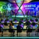 Futuristischer Konferenzraum mit Business-Leuten, die eine Präsentation zu genetischer Werbung mit DNA-Visualisierungen und digitalen Datenströmen betrachten. Die Stimmung ist angespannt und leicht ironisch.