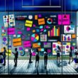 Dynamische Illustration einer Agentur: Kreatives Brainstorming mit bunten Post-its, Laptops, modernen Bildschirmen und inspirierenden Plakaten in einem urbanen, farbenfrohen Umfeld.