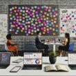 Kreatives Team brainstormt im modernen Büro vor Post-its mit Strategie- und Storytelling-Begriffen, digitalen Devices, Whiteboard und Notizbüchern.