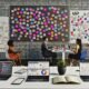 Kreatives Team brainstormt im modernen Büro vor Post-its mit Strategie- und Storytelling-Begriffen, digitalen Devices, Whiteboard und Notizbüchern.