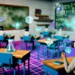 Schüler mit VR-Headsets und Haptik-Handschuhen lernen in einem futuristischen Klassenzimmer mit schwebenden digitalen Lernobjekten, während traditionelle Tafeln in den Hintergrund geraten.