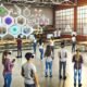 Junge Menschen lernen im futuristischen Klassenzimmer mit VR-Brillen, Tablets und Hologrammen, während Lehrkräfte sie unterstützen. Klassischer Unterricht verblasst im Hintergrund.