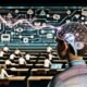 Junge Menschen verschiedener Herkunft lernen in einem Hightech-Klassenzimmer mit Headsets und Neurochips; holografische Datenströme, neuronale Netzwerke und Lehrer mit digitalen Displays zeigen die Zukunft personalisierter Bildung.